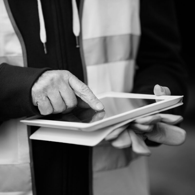 "hands of builder with small computer and gloves, selective focus on finger"