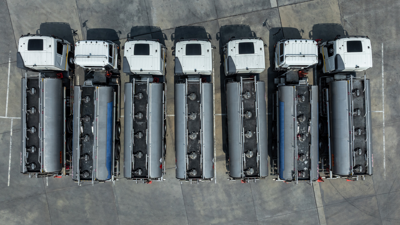 Fuel truck park on parking lot, Business oil and gas transportation and logistics with petrochemicals liquid chemical freight, Fuel tank truck transports fuel, Aerial view