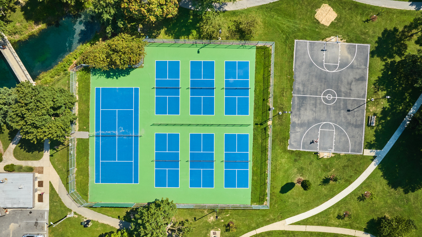 Straight down aerial tennis courts and basketball court on summer day