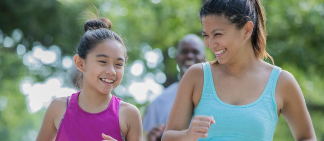 Mid adult Filipino woman and her elementary age daughter are running together in a charity marathon race event. Mother is encouraging daughter to keep going.