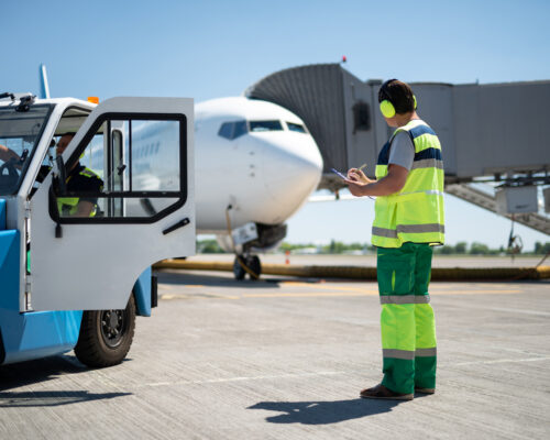 Excellent teamwork. Full length portrait of man looking at aircraft and writing information while coworker checking the vehicle
