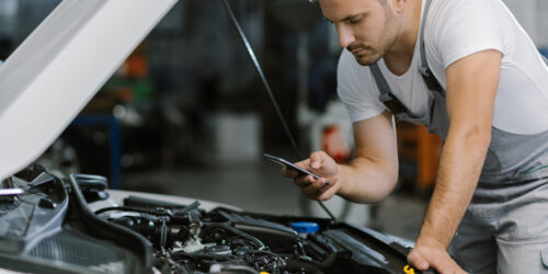 Mechanic reading a text message on smart phone in a workshop