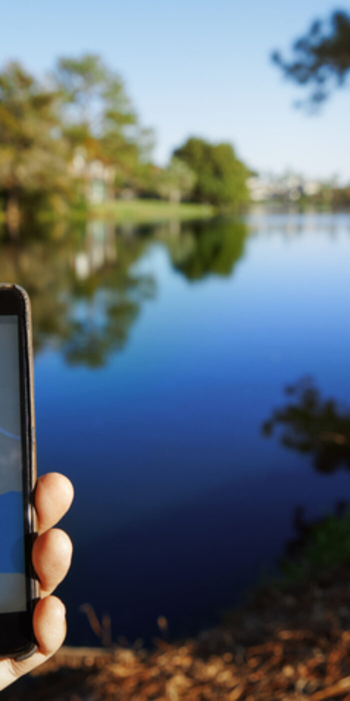 Man using mobile map app next to the lake