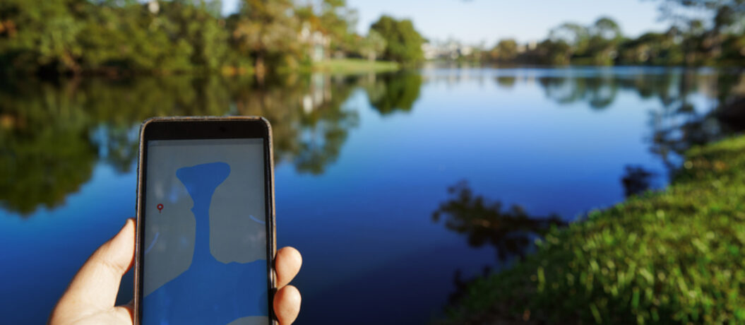 Man using mobile map app next to the lake