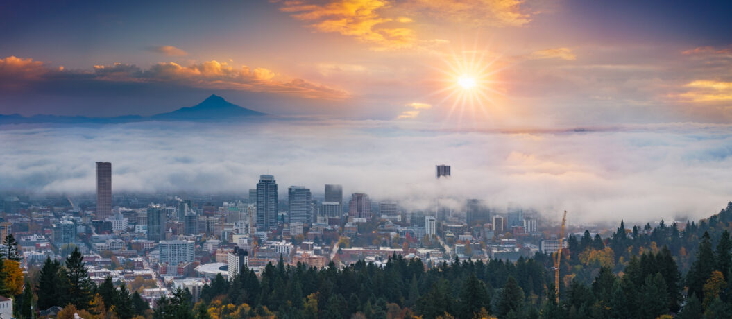 A photograph of Mt. Hood and Portland downtown with rolling fog and autumn foliage in shining sunrise and colorful clouds