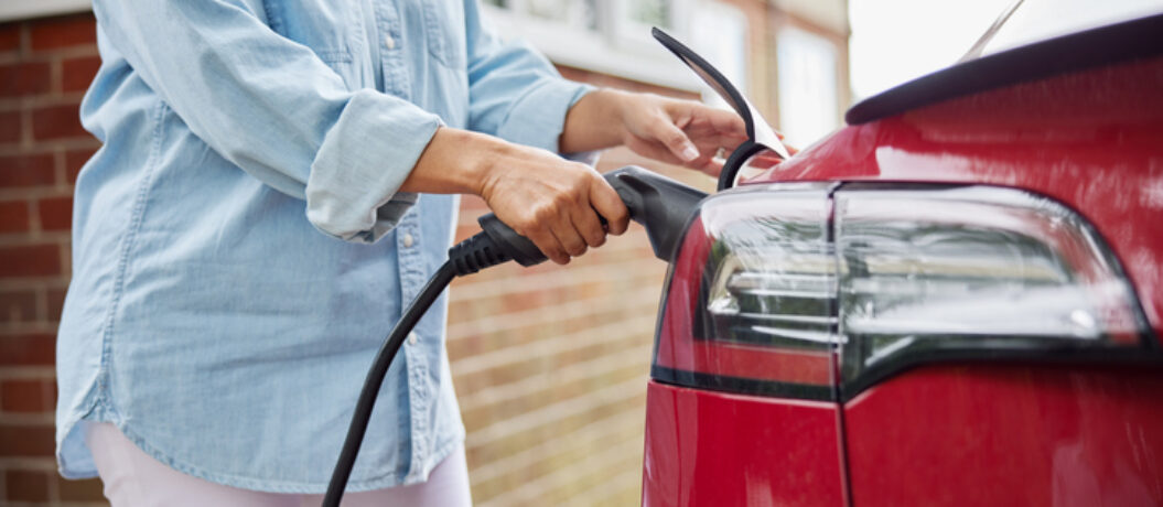 Close Up Of Woman Attaching Charging Cable To Environmentally Friendly Zero Emission Electric Car At Home