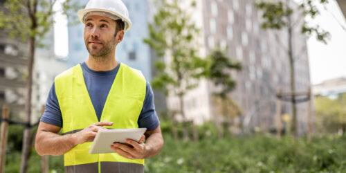 A civil engineer works on arranging parks around residential buildings, he controls the works via his tablet device