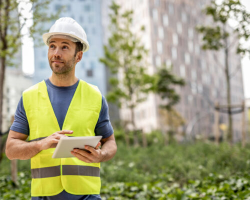 A civil engineer works on arranging parks around residential buildings, he controls the works via his tablet device