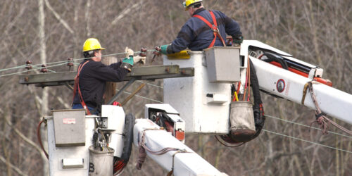 Men working on pole repairing and moving lines from a cherry picker