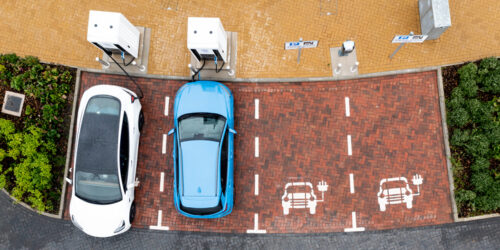 An aerial view directly above electric cars being charged at a motorway service station car charging station