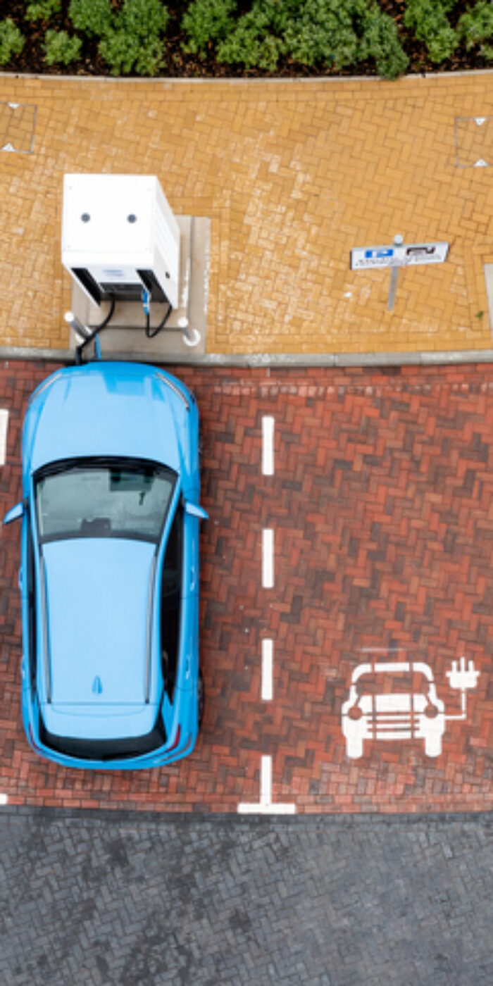 An aerial view directly above electric cars being charged at a motorway service station car charging station
