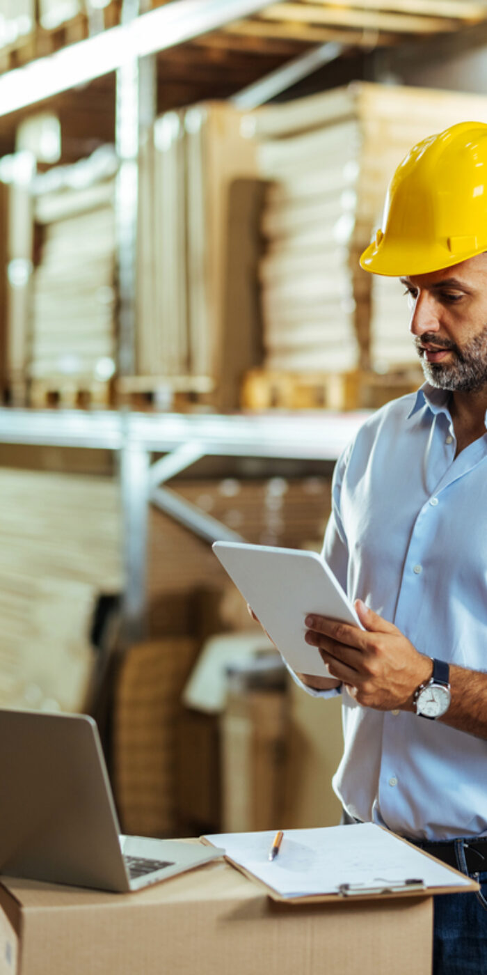 Warehouse manager working process checking the package with a tablet in a large distribution center