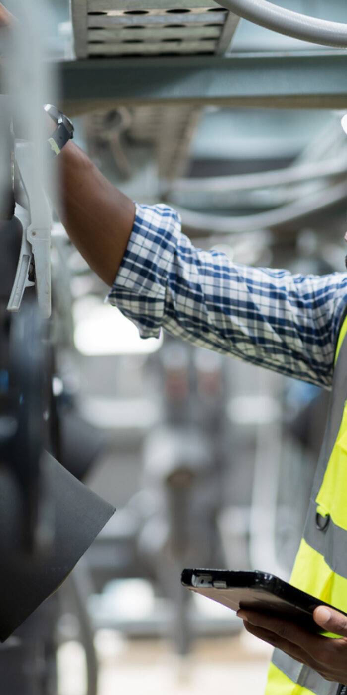 Male plumber engineer working at sewer pipes area at construction site. African American male engineer worker check or maintenance sewer pipe network system at construction sit