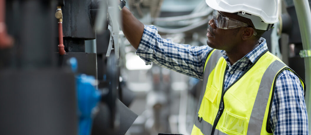 Male plumber engineer working at sewer pipes area at construction site. African American male engineer worker check or maintenance sewer pipe network system at construction sit