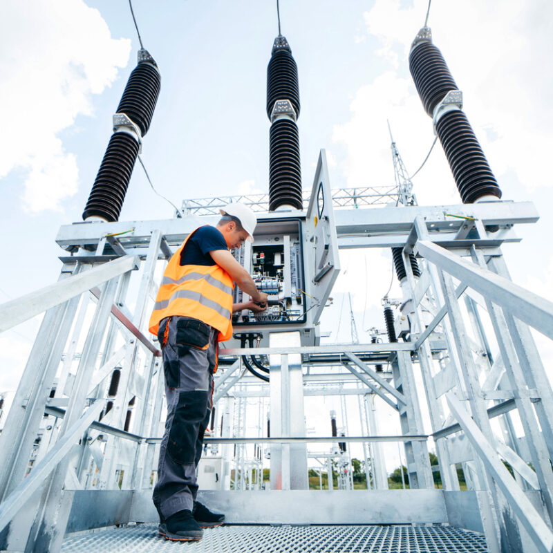 Adult electrical engineer inspect the electrical systems at the equipment control cabinet. Installation of modern electrical station