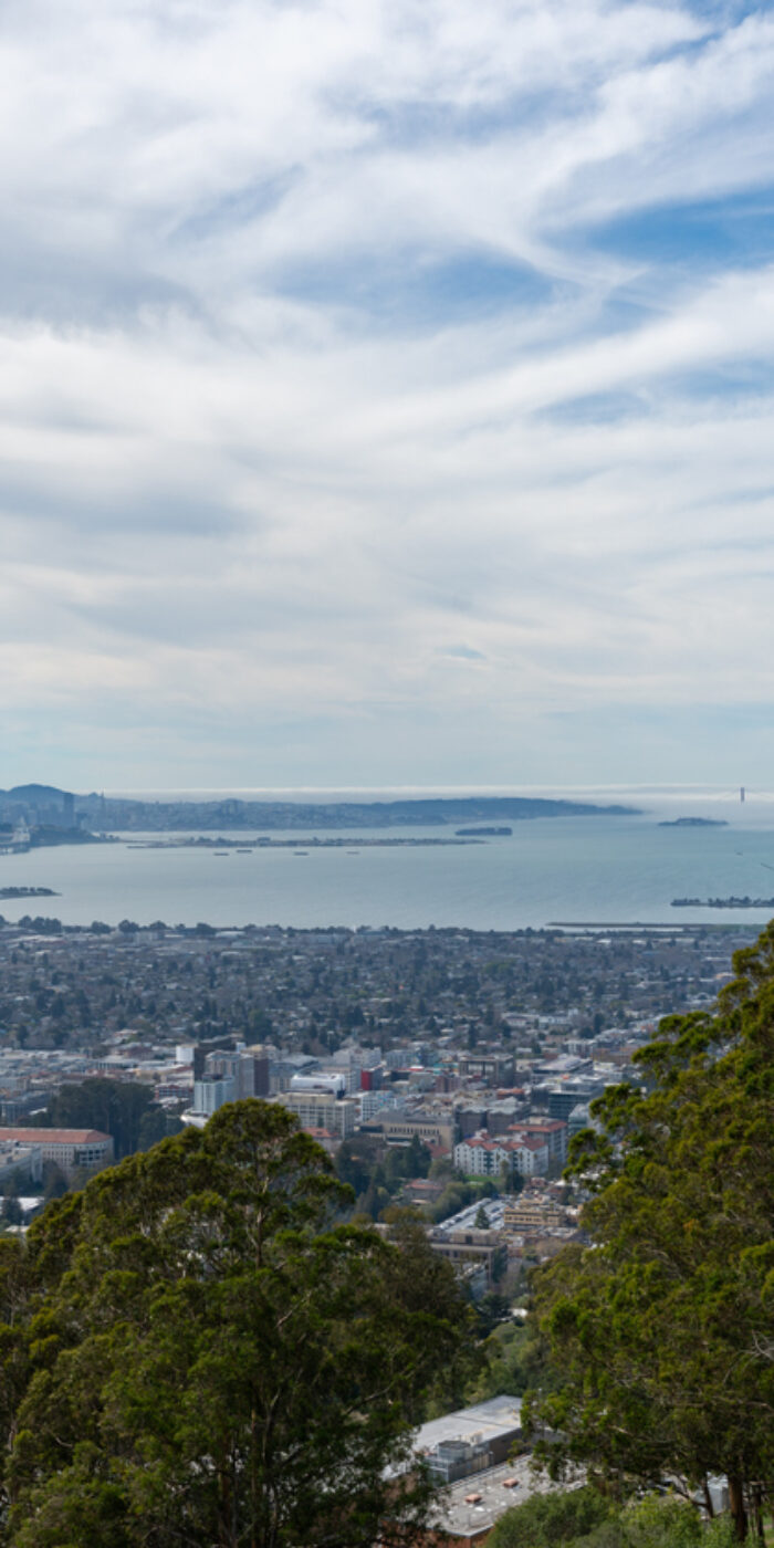View looking west across Berkeley, Oakland and the San Francisco Bay towards a foggy Golden Gate Bridge and city of San Francisco, California on a cloudy day.