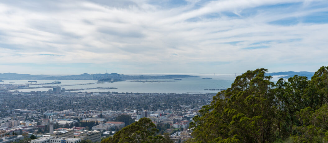 View looking west across Berkeley, Oakland and the San Francisco Bay towards a foggy Golden Gate Bridge and city of San Francisco, California on a cloudy day.