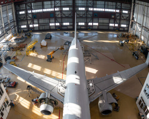 Top view of a white passenger jet plane in the aviation hangar. Airliner under maintenance. Checking mechanical systems for flight operations