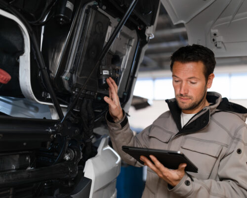 Truck mechanic is checking safety of truck.