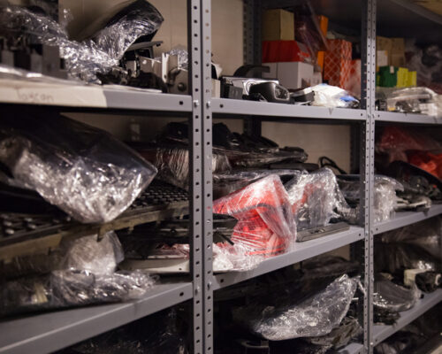Metal shelves with various car parts from new modern vehicles in an auto repair shop
