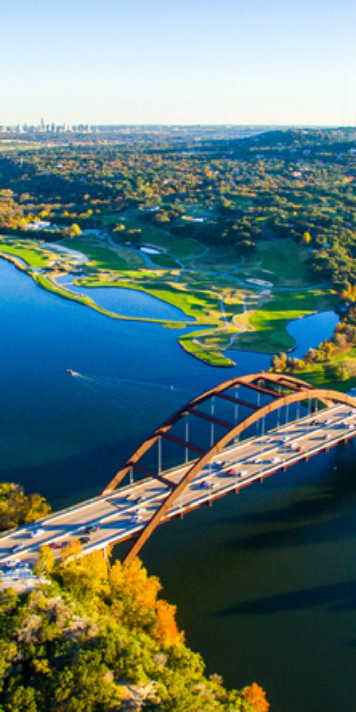 Aerial Pennybacker Bridge 360 Bridge From the Air as the leaves change colors and fall and the seasons change in central Texas. Fall turns to winter and Austin , Texas glows with bright colors of Fall and green and the Texas hill country looks amazing. This aerial breathtaking image of the Pennybacker Bridge built in 1984 and completes the Austin Vibe of West Texas Hill Country