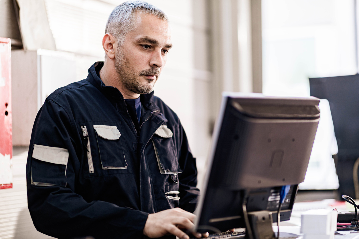 Mid adult worker using desktop PC in a workshop