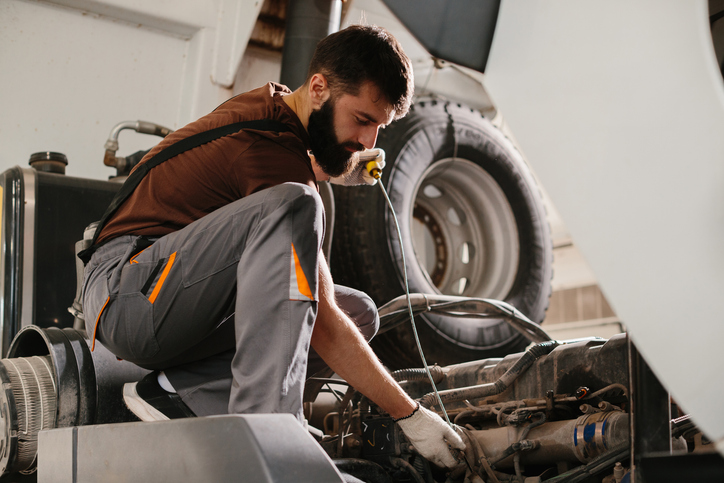 Auto mechanic repairing truck engine in garage