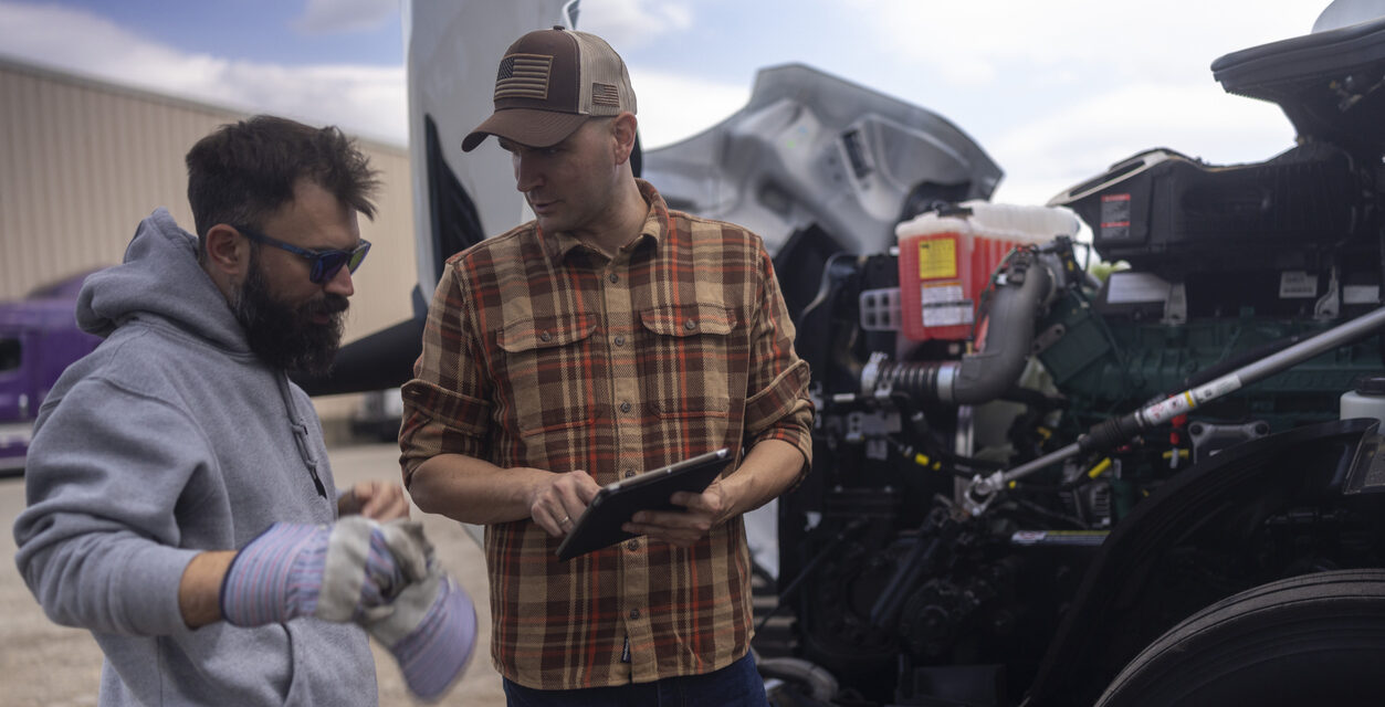 Car mechanic and truck driver using digital tablet for engine diagnostics