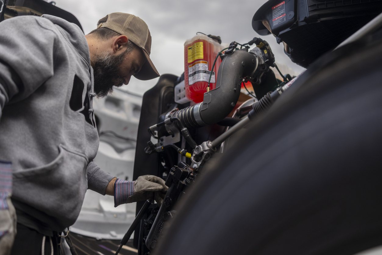 Bearded car mechanic inspecting the engine compartment of a large truck