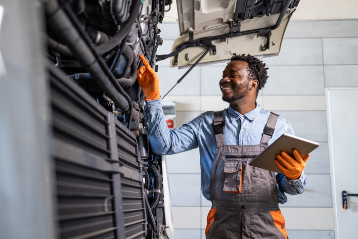 Professional truck mechanic inspecting and servicing the vehicle inside workshop
