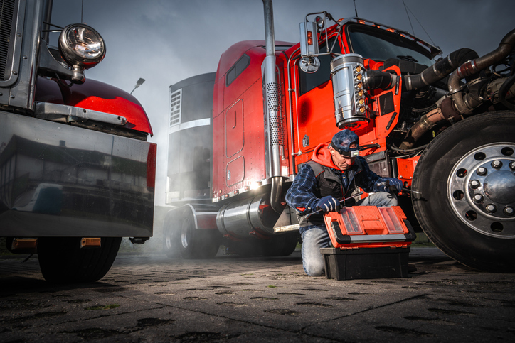 Mechanic Working on Truck With Toolbox in Urban Setting During Day
