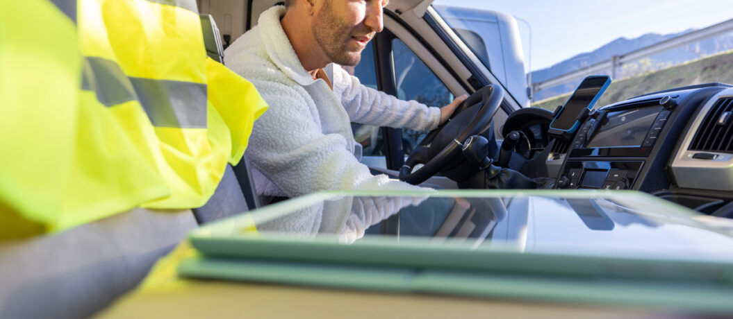 Courier driver checking his schedule on a digital tablet inside of a delivery van fleet benchmarking strategies