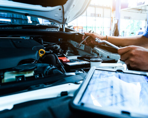 Auto mechanic are checking the condition of the car according to the month. The technician uses the tablet to check.