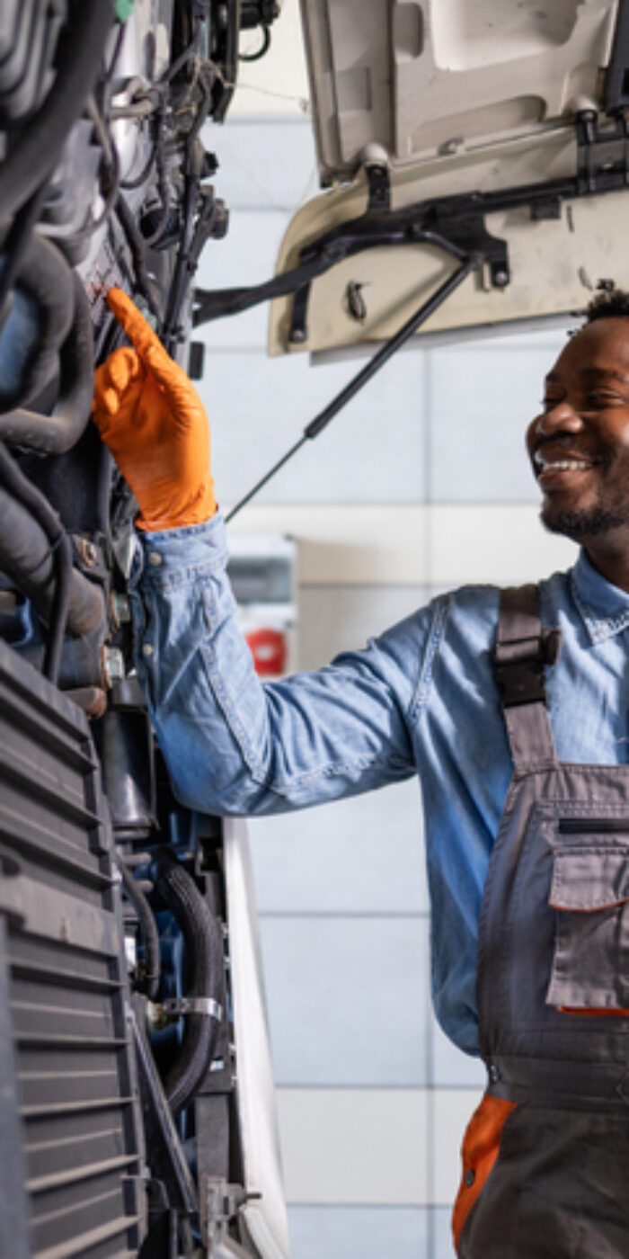 Experienced truck mechanic controlling and servicing the vehicle inside workshop.