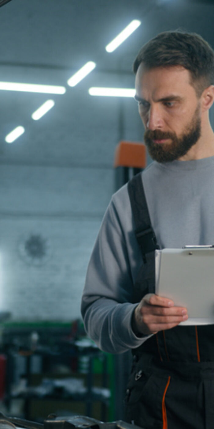 Auto mechanic professional technical expert Caucasian man male checking car manual maintenance write checklist on clipboard automobile diagnostics inspect transport at vehicle service station garage. High quality 4k footage