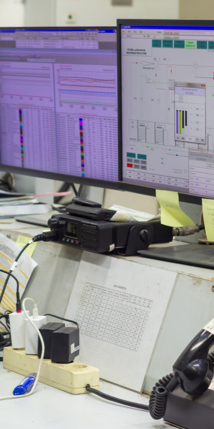 Operations center depicts various monitoring screens alongside radio transceivers and telephones, suggesting a high-stakes environment requiring constant communication