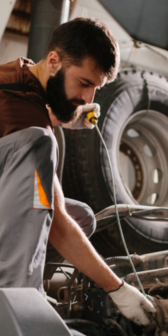Skilled auto mechanic working on a truck engine, performing maintenance and repairs in a professional garage setting