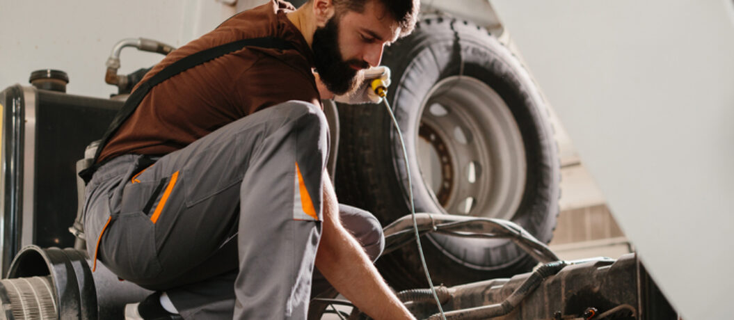 Skilled auto mechanic working on a truck engine, performing maintenance and repairs in a professional garage setting