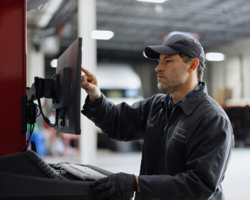 Auto mechanic working on a computer for car diagnostics in a professional repair shop, showcasing skill and precision in automotive service
