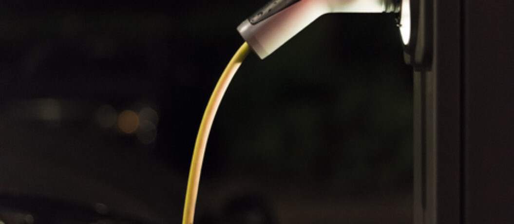 View of an Electric Car Charging Column at night and in the background a partial view of a car - Rotterdam, Netherlands